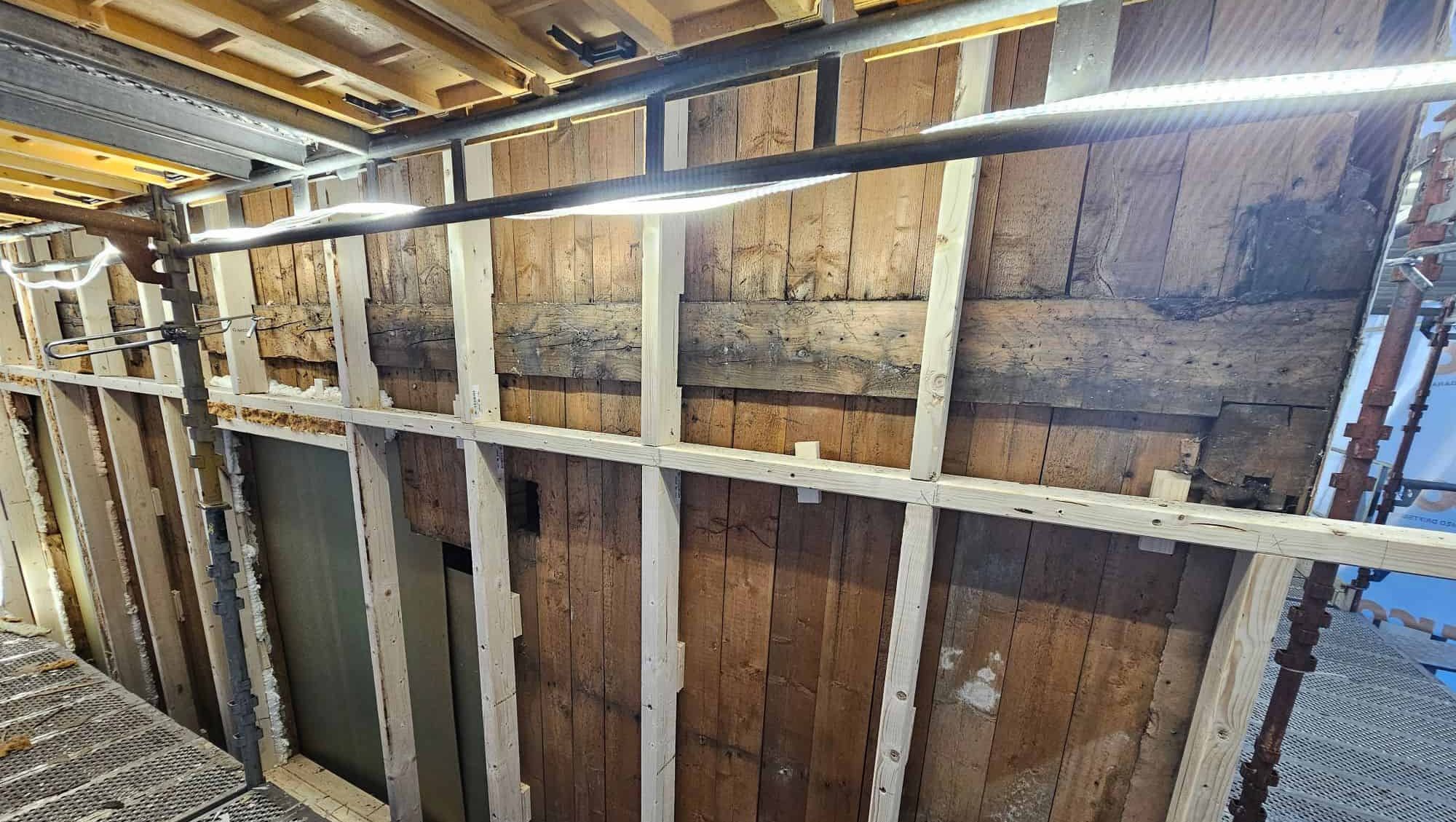 Vegg under oppgradering med nytt stenderverk montert utenpå gammel trekledning og synlige detaljer.